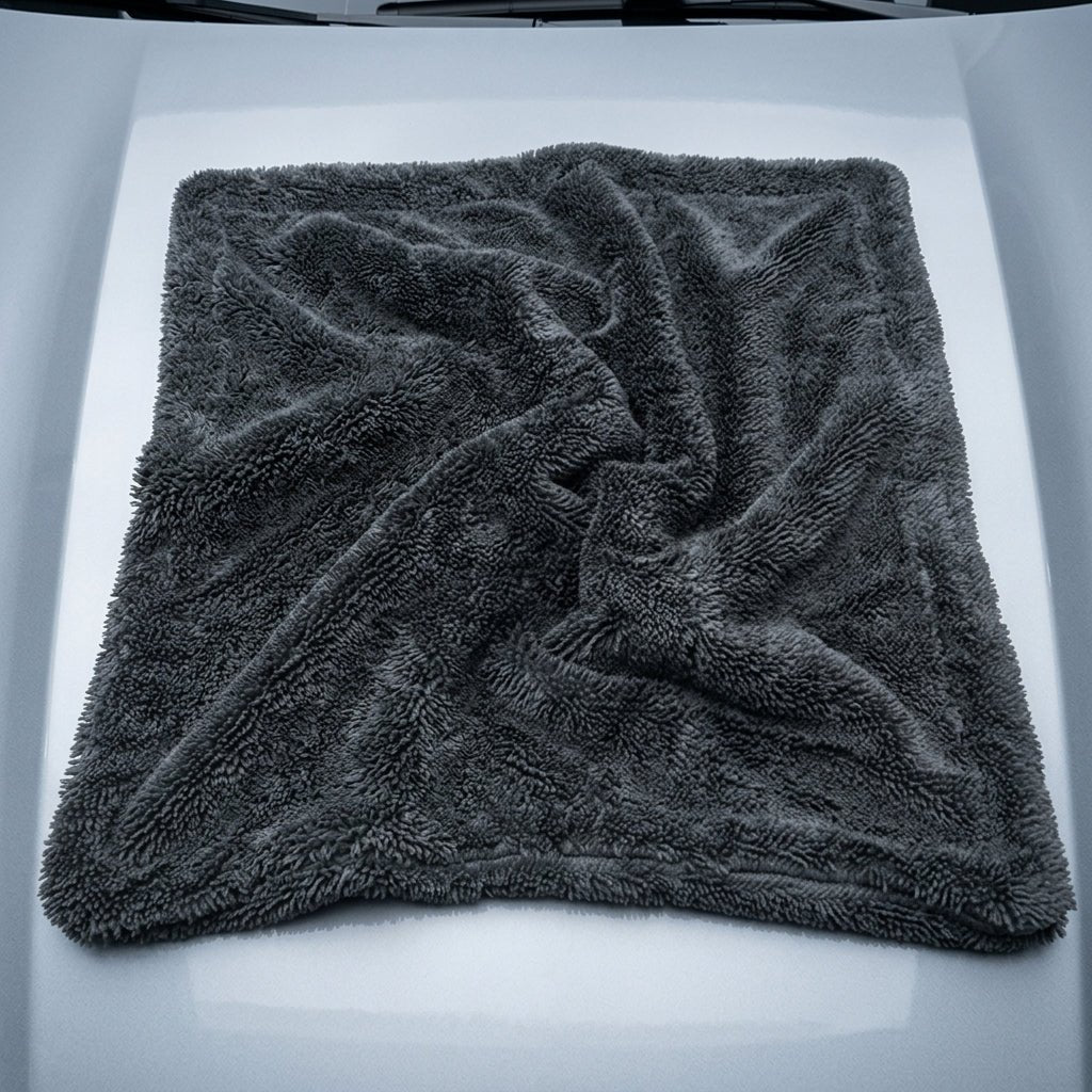 Paño de microfibra gris extendido sobre el techo de un coche blanco