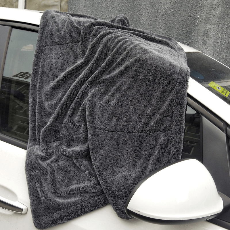 Paño de microfibra extendido sobre el lateral y el retrovisor de un coche blanco