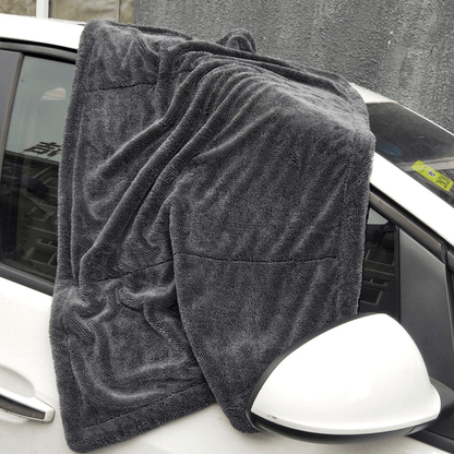 Paño de microfibra extendido sobre el lateral y el retrovisor de un coche blanco